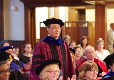 A Man In A Graduation Gown Is Clapping